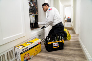 Heat Pump Services in Clearwater, FL, technician kneeling working on equipment inside hallway of home.