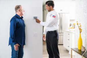Heater Replacement and Installation in Clearwater, FL, technician talking with customer adjusting thermostat.